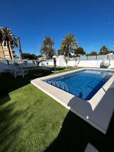una piscina en un patio con césped verde en Sea-side Villa in la Zenia, en Alicante