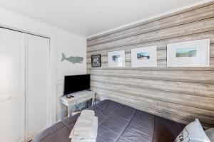 Dormitorio con pared de madera, cama y TV en The Shark Shack, en Provincetown
