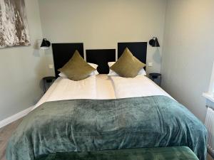 1 dormitorio con 1 cama grande con manta verde y almohadas en Northberg Apartments, en Keflavík