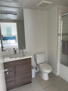 a bathroom with a toilet and a sink and a mirror at Las Palmas - Modern, Stylish, Spacious, Secure & Tranquil Condo with 2 Master Suite Bedrooms - WLK to SM Pier in Los Angeles