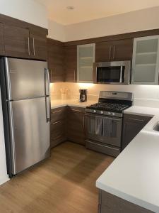 a kitchen with stainless steel appliances and wooden cabinets at Las Palmas - Modern, Stylish, Spacious, Secure & Tranquil Condo with 2 Master Suite Bedrooms - WLK to SM Pier in Los Angeles