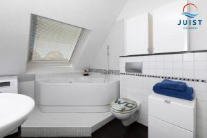 un bagno bianco con vasca e WC di Haus Hahntje 192 - Wohnung Sonnenwinkel a Juist
