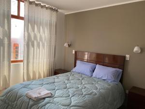 Un dormitorio con una cama grande con almohadas azules y una ventana en EL GRAN SEÑORIAL, en Jauja