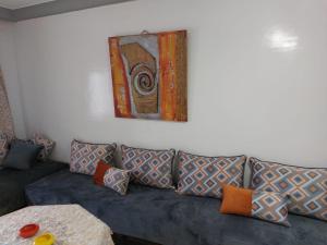 a blue couch with pillows and a painting on the wall at apartment in centre ville in Rabat