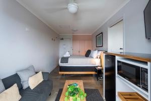 una pequeña sala de estar con cama y sofá en Yamba Views Angourie Room 11, en Yamba