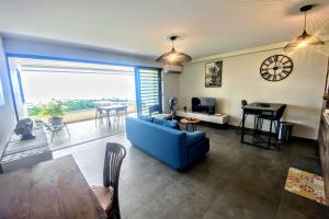 a living room with a blue couch and a table at Near Papeete modern apartment with sea view in Papeete +14 photos