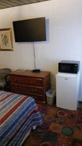 een slaapkamer met een bed en een tv aan de muur bij White Pine Motel in Ely