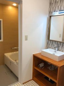 een badkamer met een wastafel, een bad en een spiegel bij 金澤華ゆり in Kanazawa