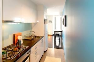 cocina con armarios blancos y nevera blanca en Relaxing, light-filled city apartment, en Melbourne