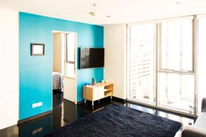 Habitación con pared de acento azul y TV. en Relaxing, light-filled city apartment, en Melbourne