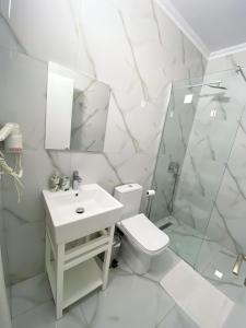 a white bathroom with a toilet and a sink at Hotel Abedini in Sarandë