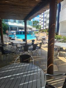 um pátio exterior com mesas e cadeiras e uma piscina em Rio Quente Aguas da Serra Apart em Rio Quente