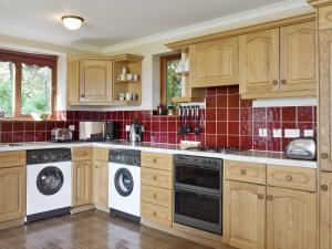 a kitchen with wooden cabinets and white appliances at Sleepy Hollow - Smmc in Balmacara