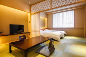 a bedroom with a bed and a table and a tv at Hotel Honnoji in Kyoto