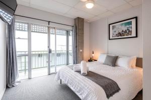 Un dormitorio con una cama blanca y una ventana grande. en Yamba Views Angourie Views Apartment, en Yamba