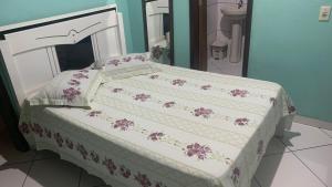 a bed with a white bedspread with purple flowers on it at Pousada Da Lú in Lençóis