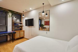 a bedroom with a bed and a tv and a mirror at Hotel POCO Seongsu in Seoul