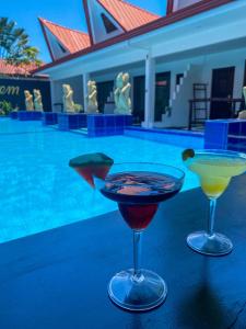 two cocktails sitting on a table next to a swimming pool at Carpe Diem Villas & Resort in Puerto Princesa City