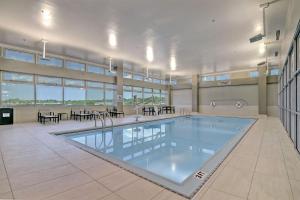 a large pool in a building with tables and chairs at Tulsa Marriott Southern Hills in Tulsa
