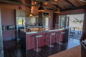 a kitchen with a large island with bar stools at Holiday Bliss in Tirau