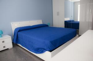 Dormitorio azul con cama blanca y espejo en Case Vacanze Adelaide, en Cefalú