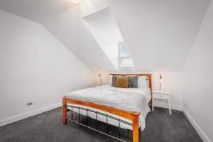 ホバートにあるBrisbane Terrace - 3 Bedroom Hobart Inner City - Free Parkingの白いベッドルーム(ベッド1台、窓付)