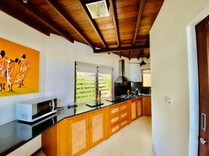 a kitchen with white walls and a wooden ceiling at Lembongan Harmony Villas in Nusa Lembongan