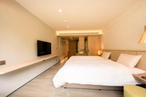 鹿谷的住宿－溪頭福華渡假飯店，卧室配有一张白色大床和一台平面电视。