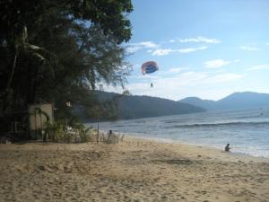 a person flying a kite on the beach at ET Budget Guest House in Batu Ferringhi