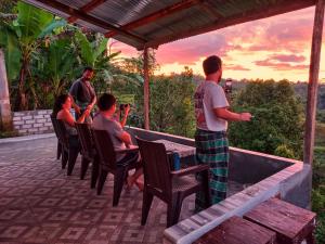 a group of people sitting around a table on a patio at Sun Rice Homestay in Ruteng