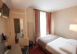 um quarto de hotel com uma cama, uma secretária e uma janela em Hôtel Eiffel Kensington em Paris