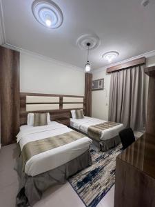 a hotel room with two beds and a tv at أجنحة ورد للشقق المخدومة in Khamis Mushayt