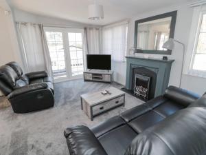 a living room with a leather couch and a fireplace at Betty's Lodge in Morpeth