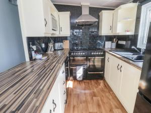 a kitchen with white cabinets and a wooden counter top at Betty's Lodge in Morpeth
