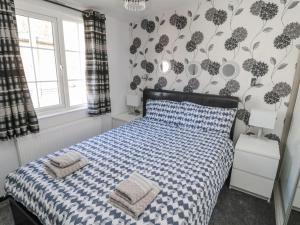 a bedroom with a bed with a blue and white comforter at Betty's Lodge in Morpeth