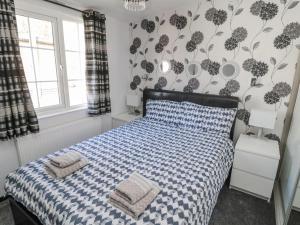 a bedroom with a bed with a blue and white comforter at Betty's Lodge in Morpeth