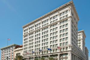 Un grande edificio bianco con bandiere americane sopra. di The Ritz-Carlton, New Orleans a New Orleans