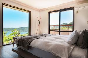 sypialnia z dużym łóżkiem i dużymi oknami w obiekcie プライベートリゾート日暖 w mieście Taga