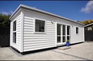 une petite maison blanche assise sur un patio dans l'établissement BENROSE FARM COTTAGES, à Wellington