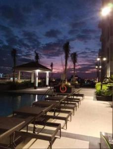 a row of benches next to a pool at night at Coast Residences Penthouse with skyline and manila bay view in Manila