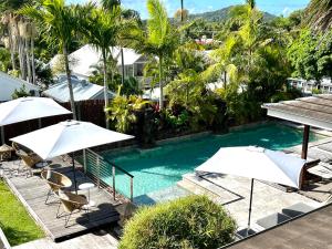 a swimming pool with umbrellas and chairs and trees at Aabi's at Byron in Byron Bay