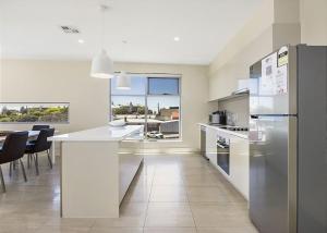 a kitchen with a refrigerator and a table with chairs at Salt 18 Luxury Sorrento Penthouse in Sorrento