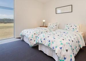 a bedroom with two beds and a large window at St Andrews Beach apartment 4 01 in Fingal