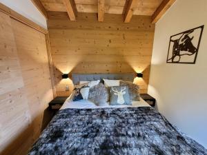 ein Bett in einem Zimmer mit einer Holzwand in der Unterkunft Appartement 4* avec 2 suites, balcon, garage, accès rapide aux pistes, WiFi - FR-1-598-139 in Les Gets