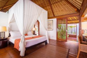 a bedroom with a bed with a mosquito net at Mayaloka Villas in Seminyak