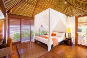 a bedroom with a canopy bed in a room with windows at Mayaloka Villas in Seminyak