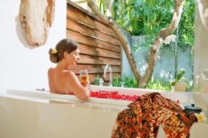 a woman sitting in a bath tub with a glass of wine at Mayaloka Villas in Seminyak