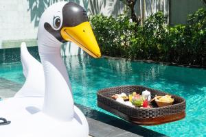 a swan statue with a tray of food next to a pool at Mayaloka Villas in Seminyak
