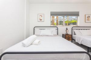 1 dormitorio blanco con 2 camas y ventana en One Bedroom Apartment - with Parking & Balcony - Heart of Wynwood, en Miami