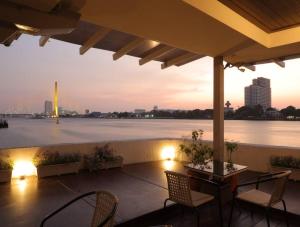 un patio con sillas y vistas al agua en Riverfront house/Chao phraya river/Baan Rimphraya en Bangkok